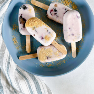 Mini blueberry cheesecake popsicles on a blue plate.