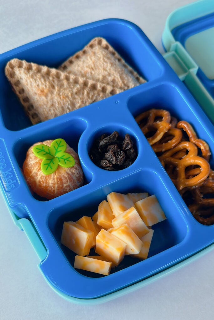 Almond butter banana uncrustables served with a mandarin raisins, pretzels, and cubed cheese.