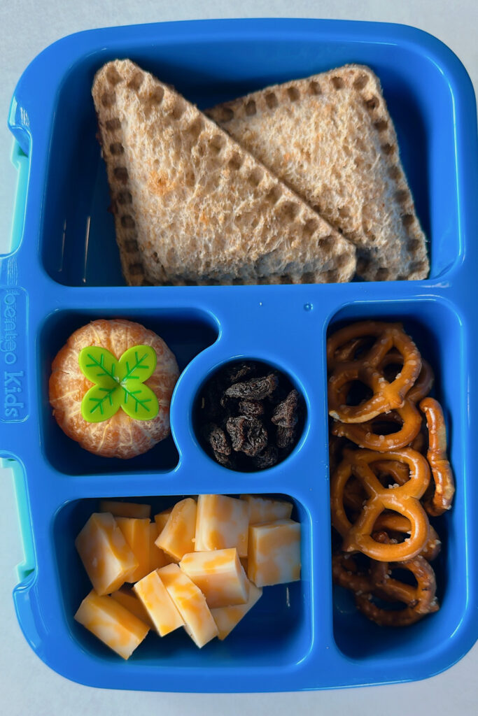 Almond butter banana uncrustables served with a mandarin raisins, pretzels, and cubed cheese.