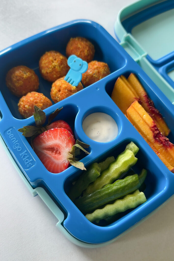 Cheesy carrot bites served with cucumbers, ranch dip, strawberries, and peaches.