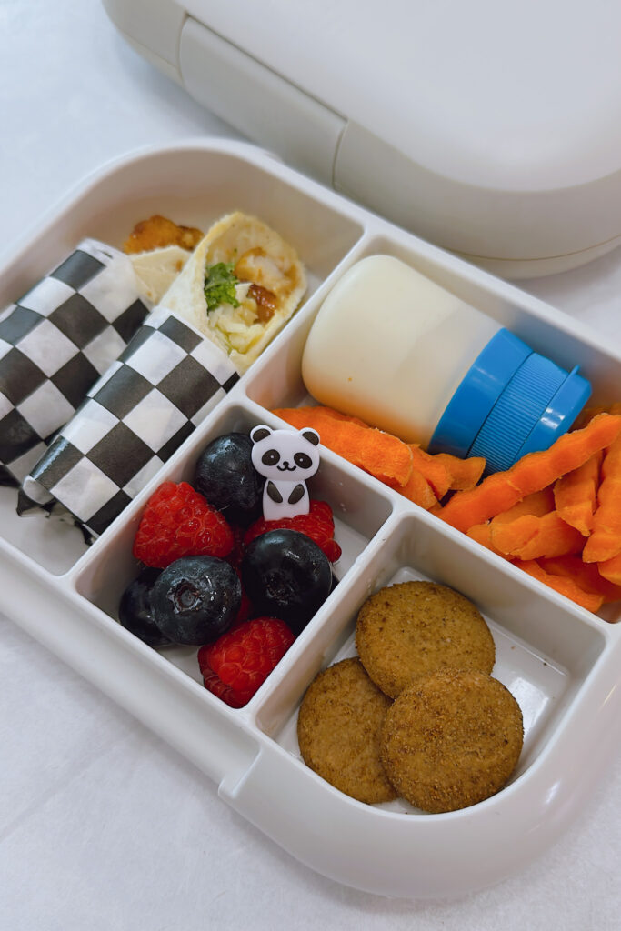 Crispy chicken wraps served with carrots, ranch dip, raspberries, blueberries, and mini cookies.