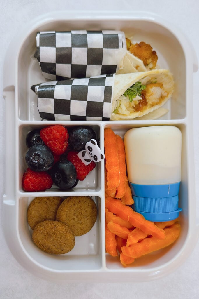 Crispy chicken wraps served with carrots, ranch dip, raspberries, blueberries, and mini cookies.