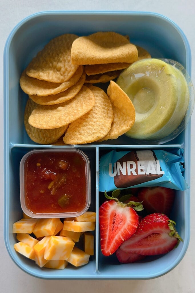 Tortilla chips served with salsa, guacamole, cheese cubes, strawberries and a mini chocolate bar.