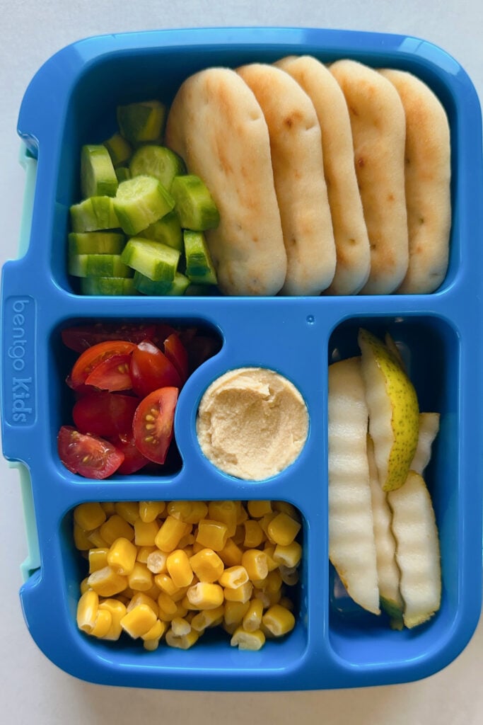 Naan dippers served with hummus, cucumber, tomatoes, corn, and pears.