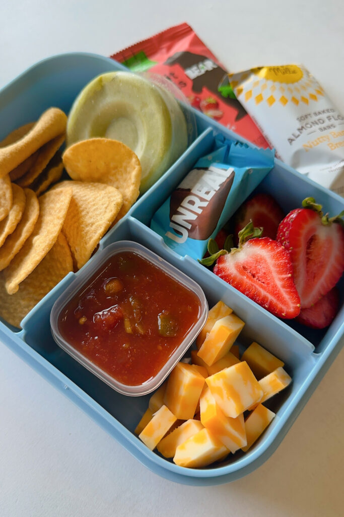 Tortilla chips served with salsa, guacamole, cheese cubes, strawberries and a mini chocolate bar.