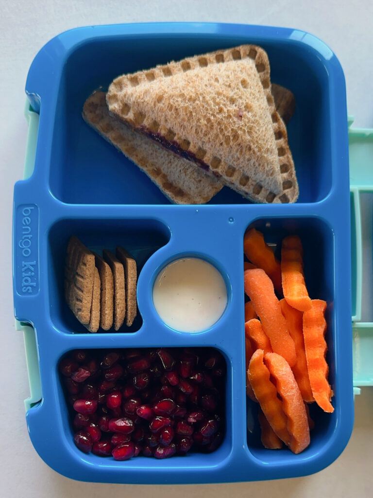 Peanut butter and jelly uncrustables served with carrots, ranch dip, pomegranate seeds and graham crackers.