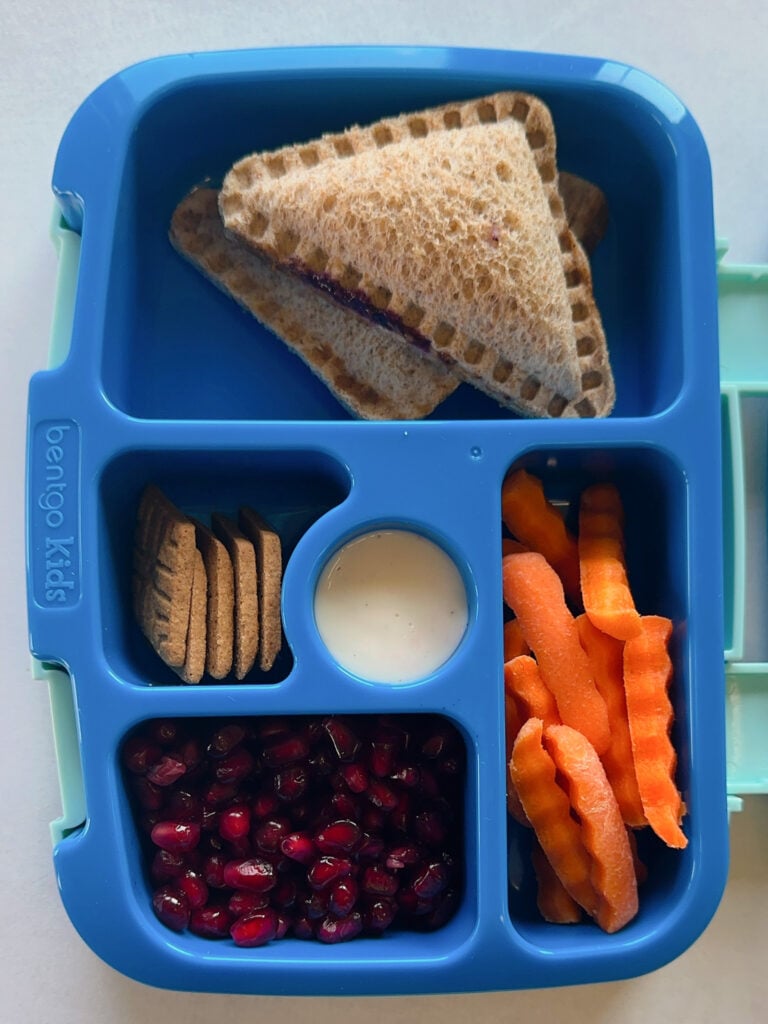 Peanut butter and jelly uncrustables served with carrots, ranch dip, pomegranate seeds and graham crackers.