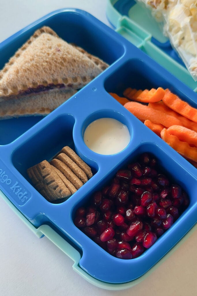 Peanut butter and jelly uncrustables served with carrots, ranch dip, pomegranate seeds and graham crackers.