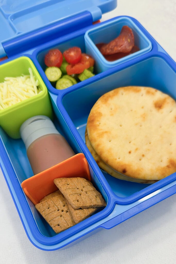 Naan rounds served with pizza sauce, mozzarella cheese, cucumbers, grapes, pepperoni, and graham crackers.