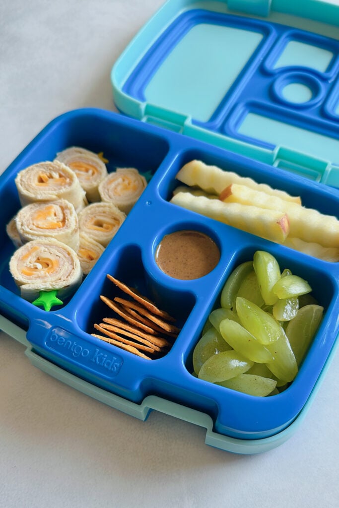 Turkey and cheese rollups served with apples, granola butter, cheese crackers and grapes.