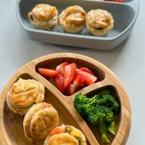 Mini chicken pot pies served with strawberries and broccoli.