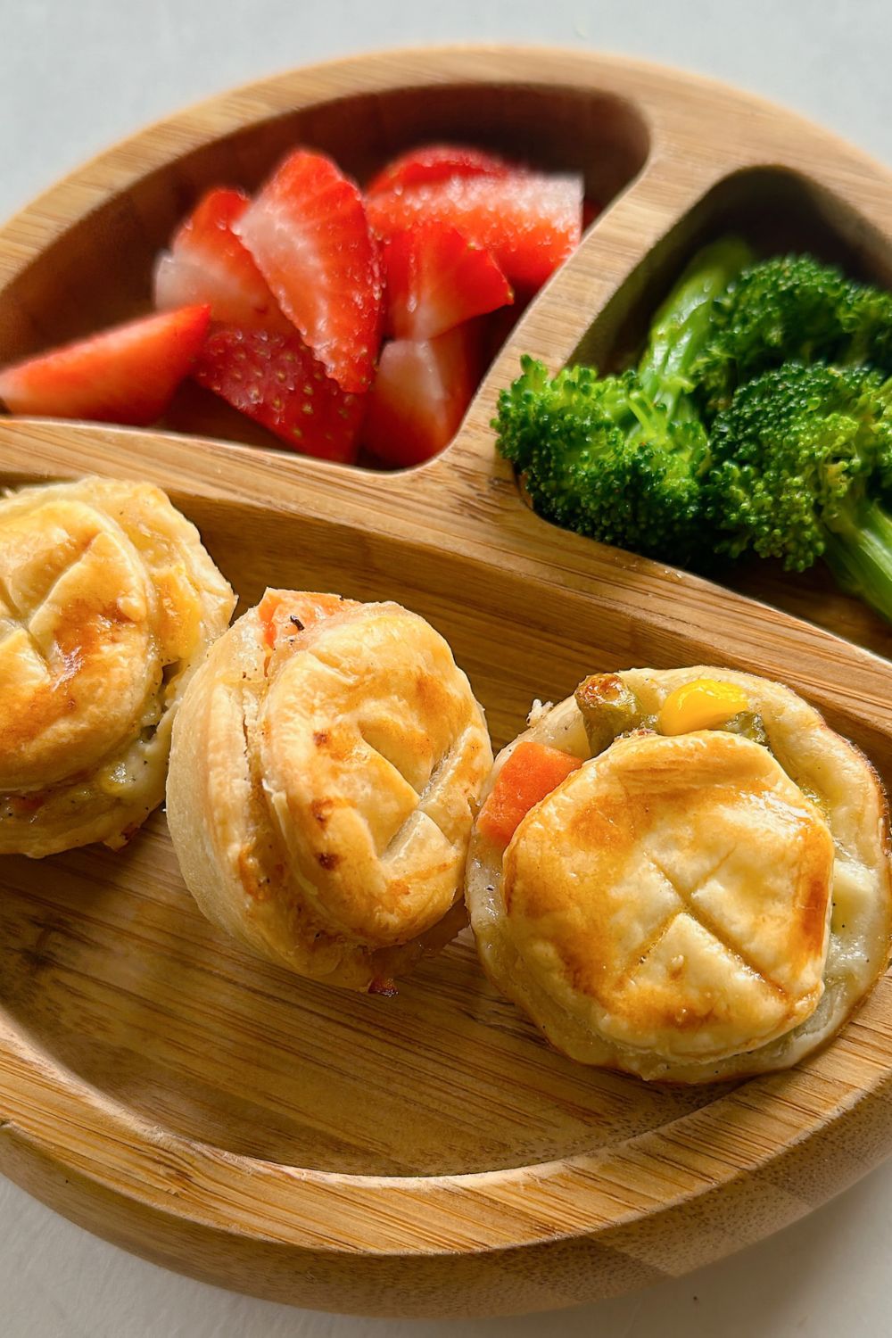 Mini chicken pot pies served with strawberries and broccoli.