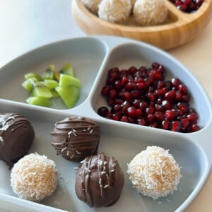 Coconut balls served with kiwi chunks and pomegranate seeds.