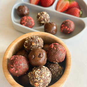 Chocolate balls in a bowl and served with strawberries.