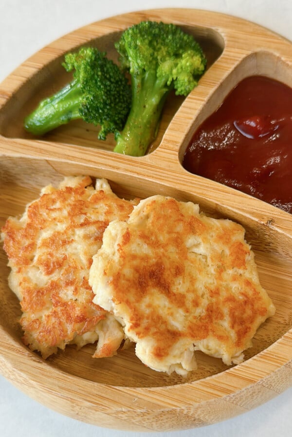 Chicken fritters served with broccoli and ketchup.