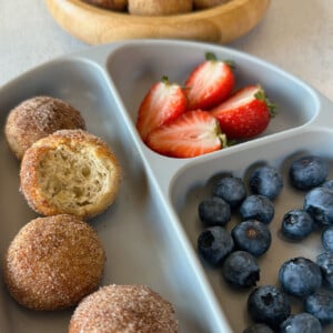 Air fryer donut holes served with strawberries and blueberries.