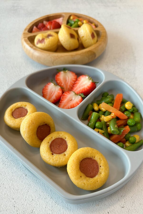 Mini corndog bites served with mixed vegetables and strawberries.