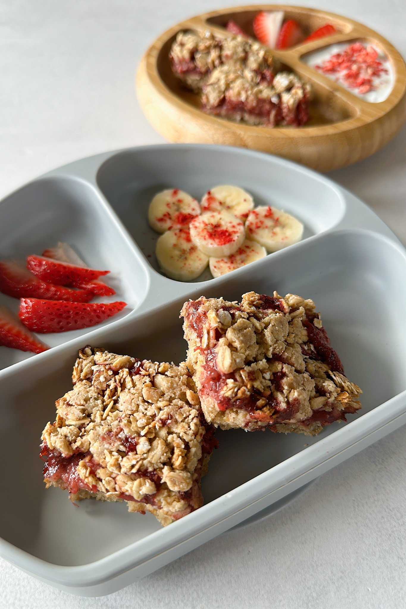 Strawberry crumble bars served with bananas, strawberries, and yogurt.