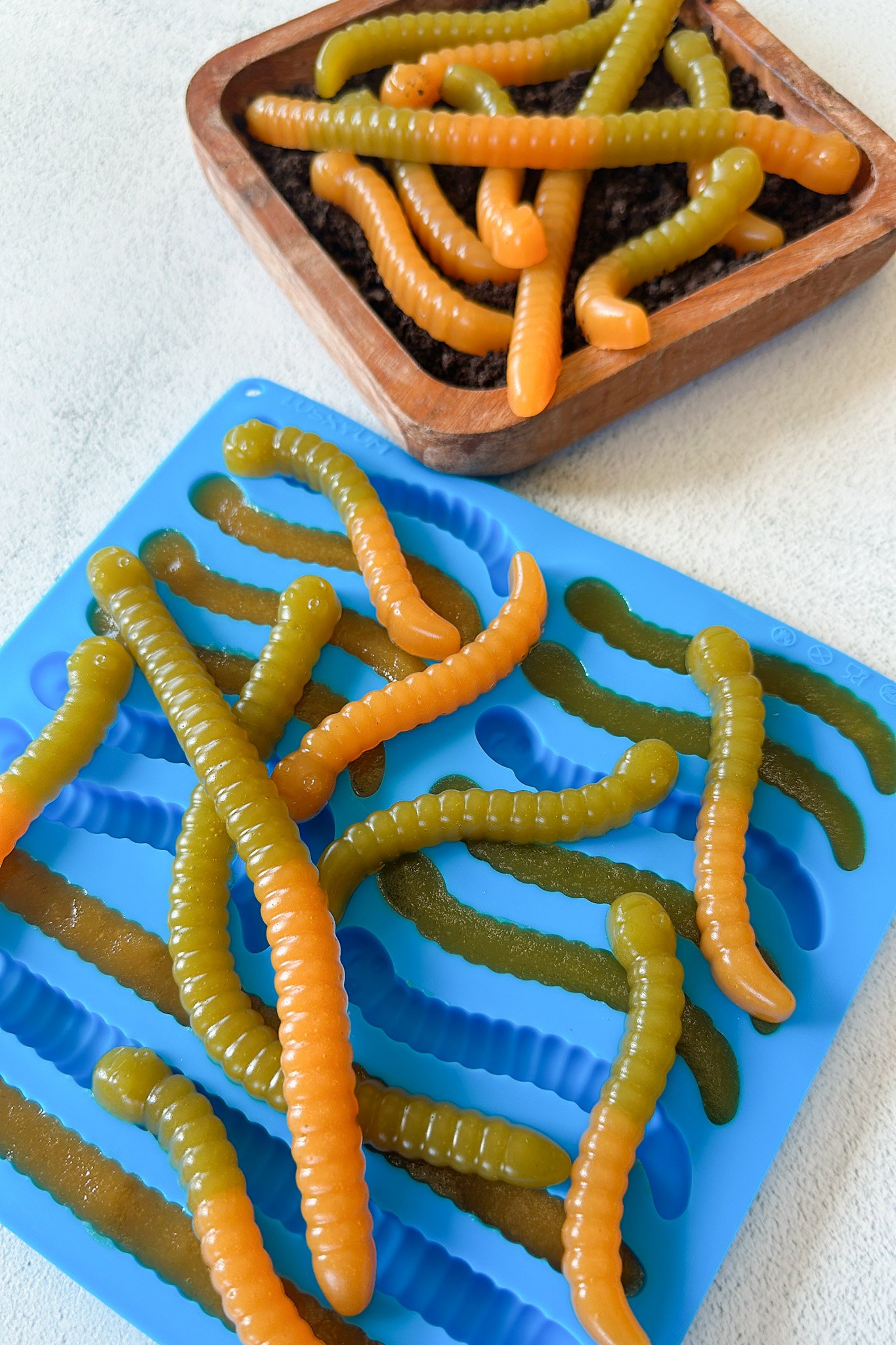 Gummy worms served on a plate with crushed up cookies.