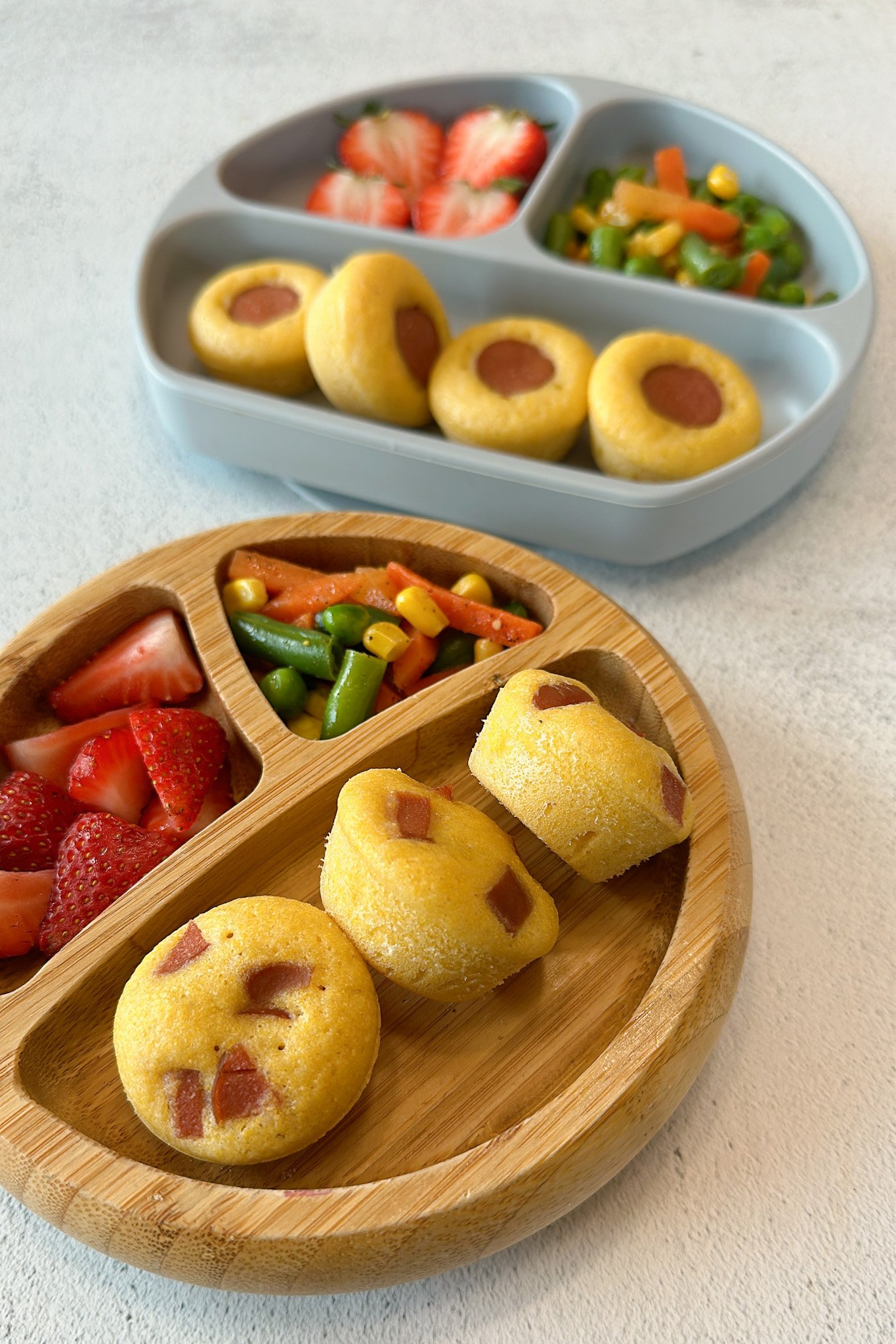 Mini corndog bites served with mixed vegetables and strawberries.