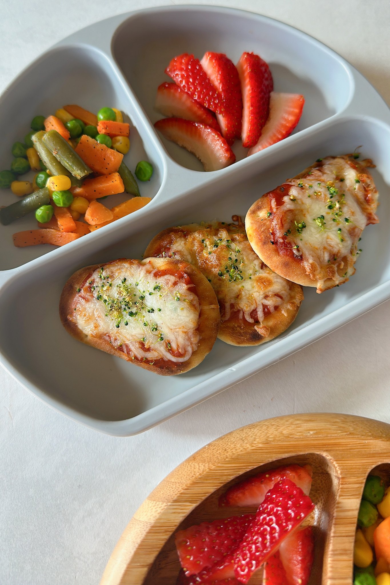 Air fryer naan pizzas served with strawberries and mixed vegetables.
