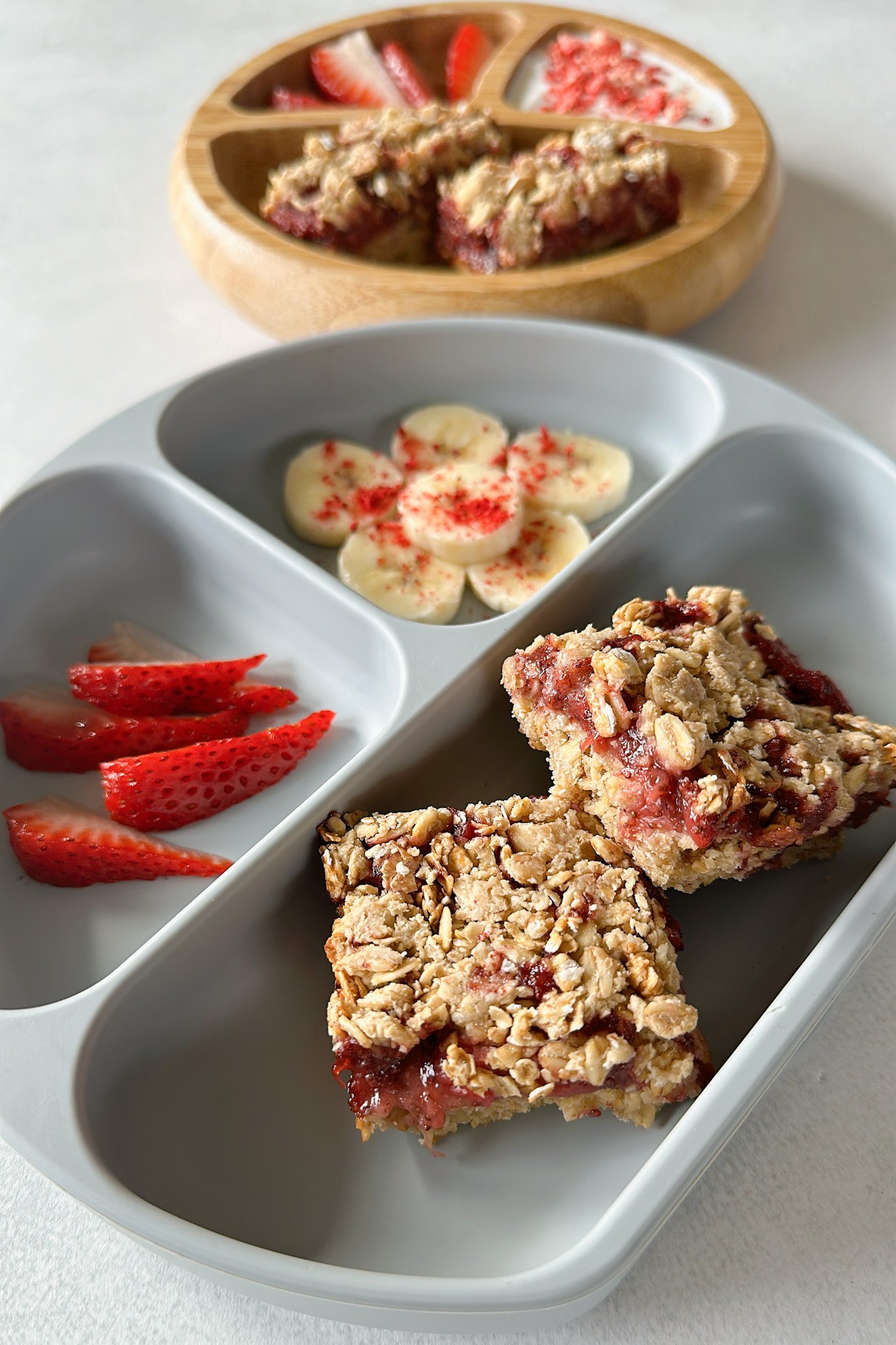 Strawberry crumble bars served with bananas, strawberries, and yogurt.