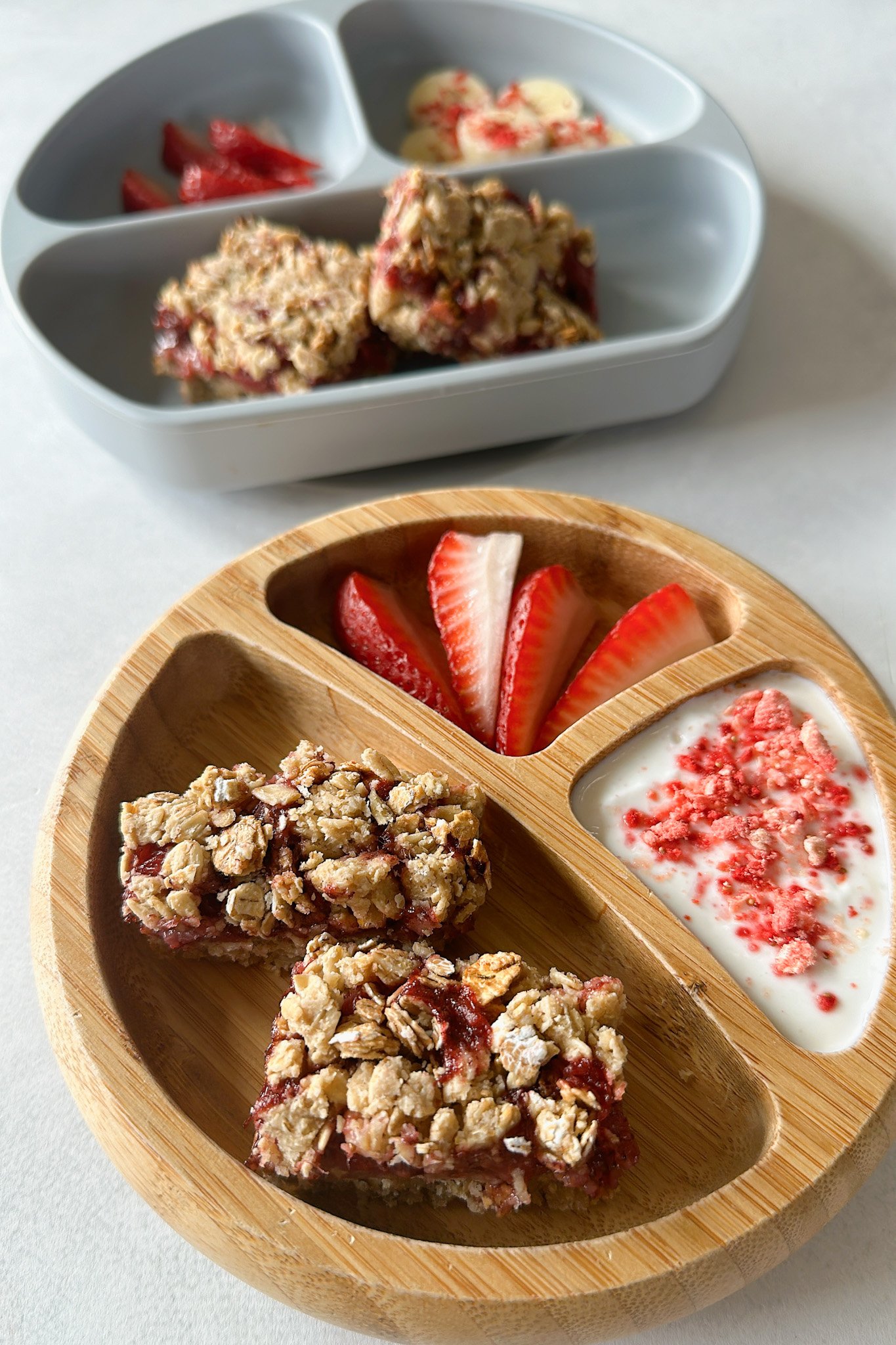 Strawberry crumble bars served with bananas, strawberries, and yogurt.