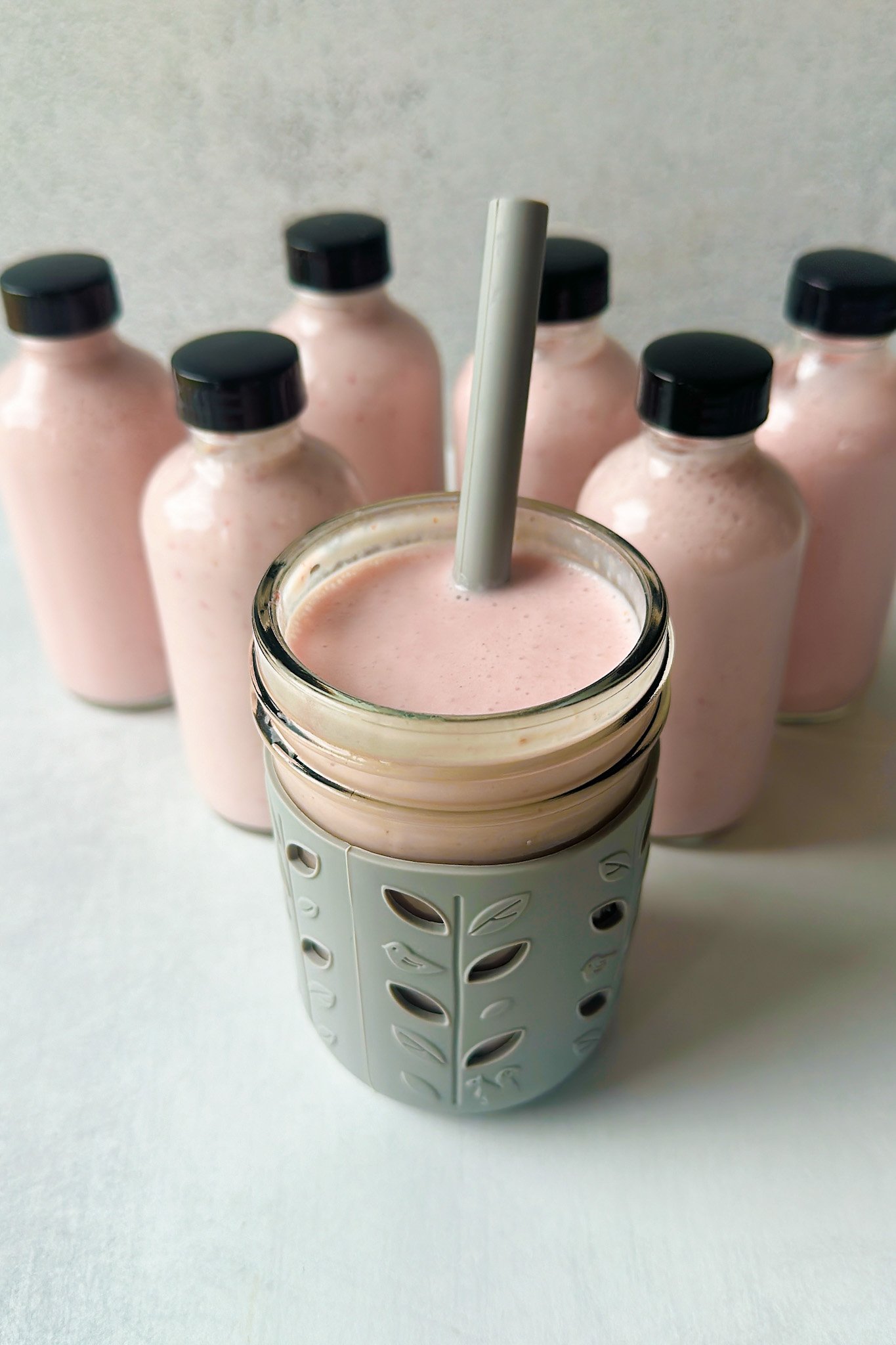 Homemade strawberry yogurt drinks shown in mini glass jars.