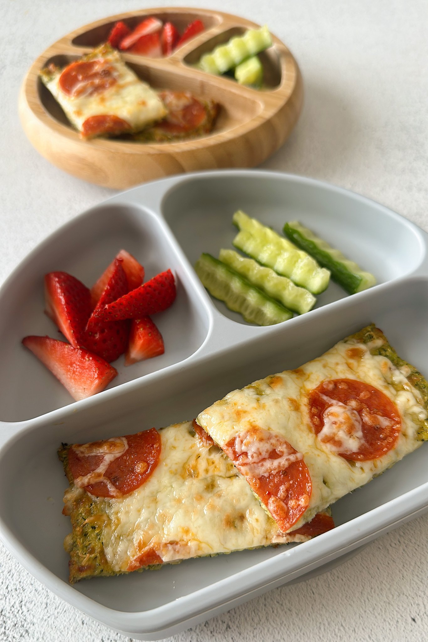 Cheesy zucchini flatbread served with strawberries and cucumbers.