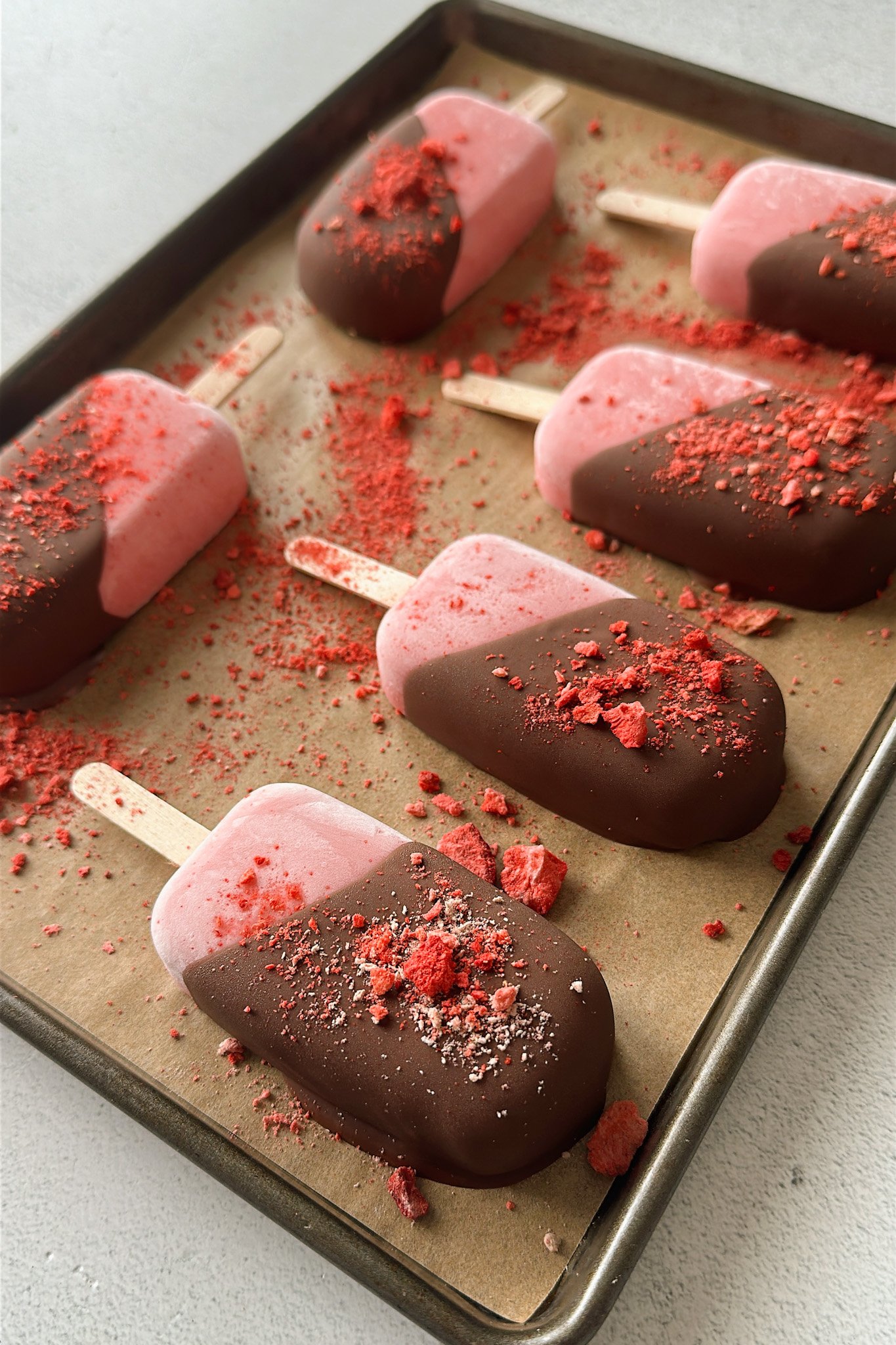 Frozen strawberry yogurt bars half dipped in chocolate.