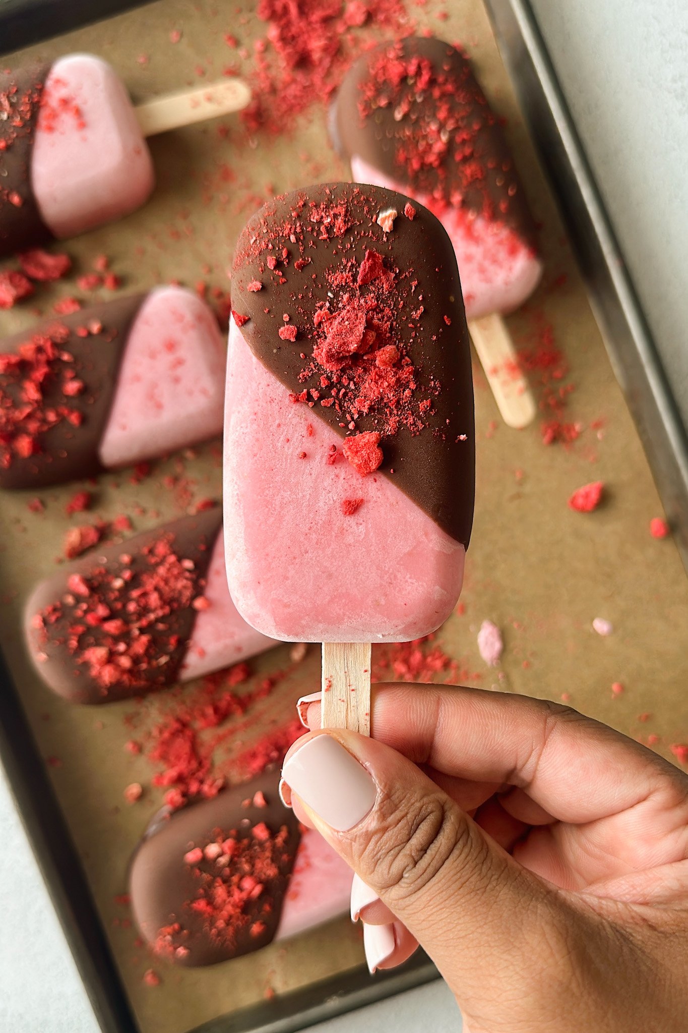 Frozen strawberry yogurt bars half dipped in chocolate.
