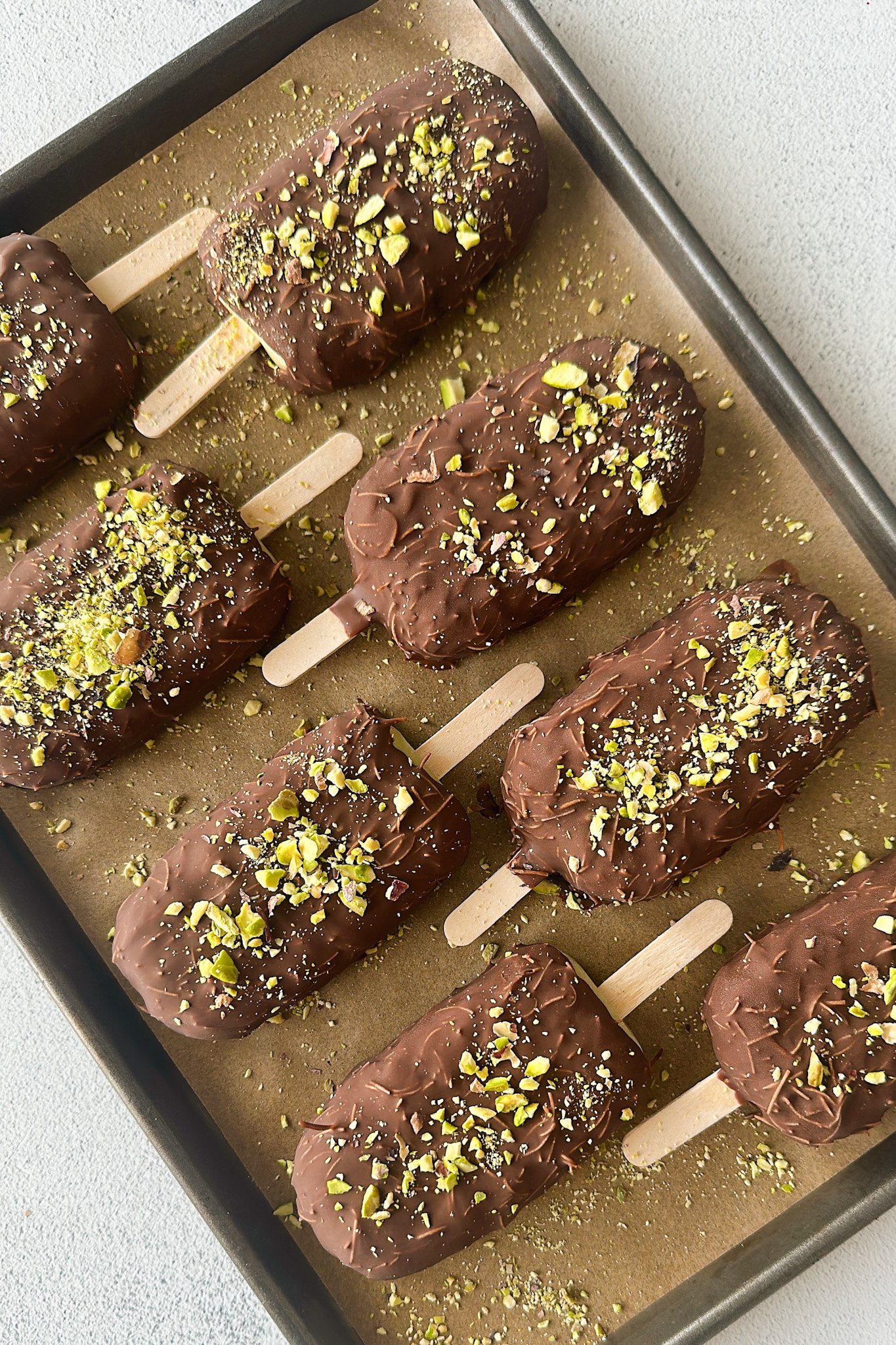 Pistachio ice cream bars on a baking sheet.