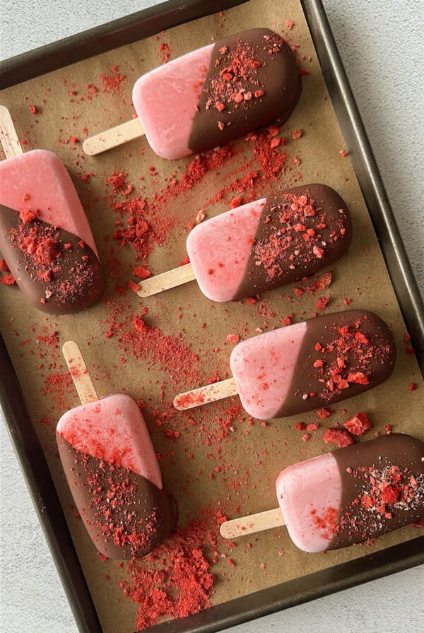 Frozen strawberry yogurt bars half dipped in chocolate.