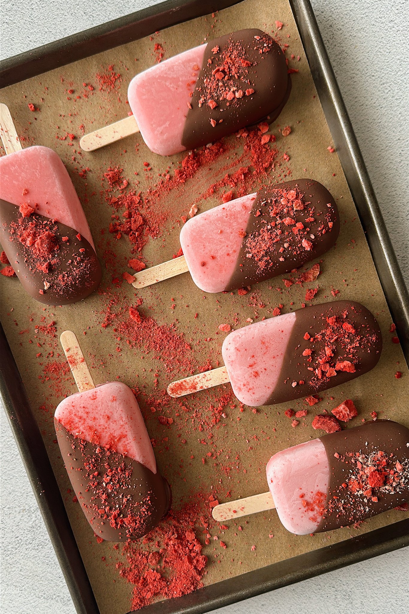 Frozen strawberry yogurt bars half dipped in chocolate.