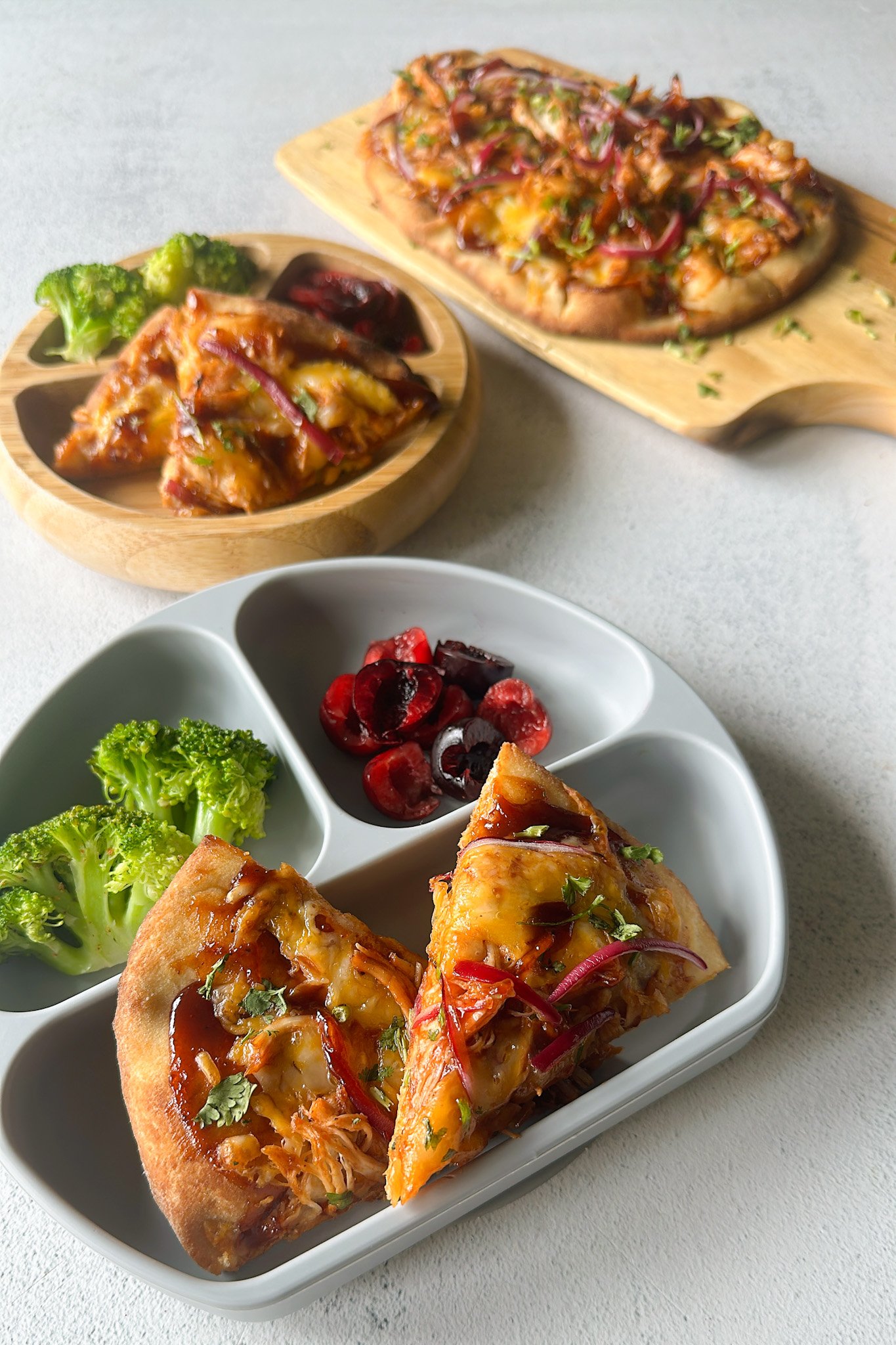 BBQ chicken naan pizzas served with broccoli and cherries.