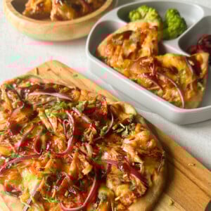 BBQ chicken naan pizzas served with broccoli and cherries.