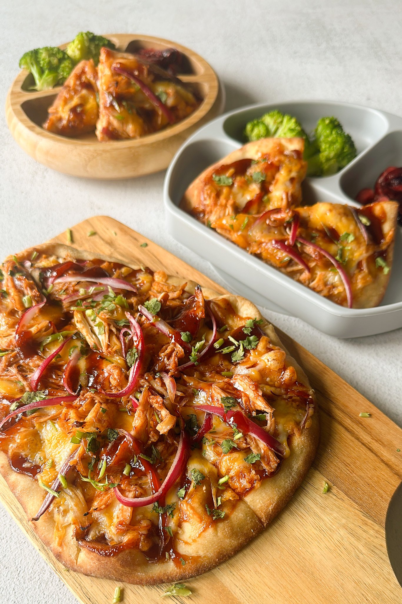 BBQ chicken naan pizzas served with broccoli and cherries.