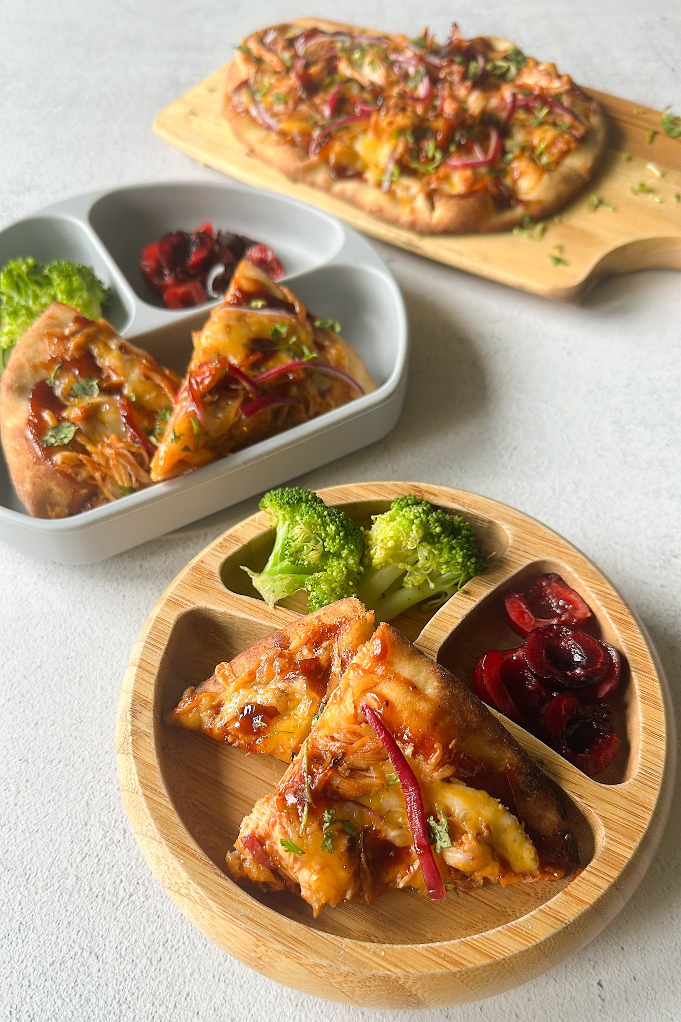 BBQ chicken naan pizzas served with broccoli and cherries.