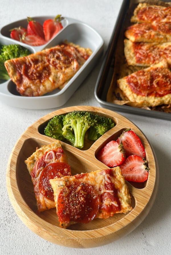 Chicken crust pizza served with broccoli and strawberries.
