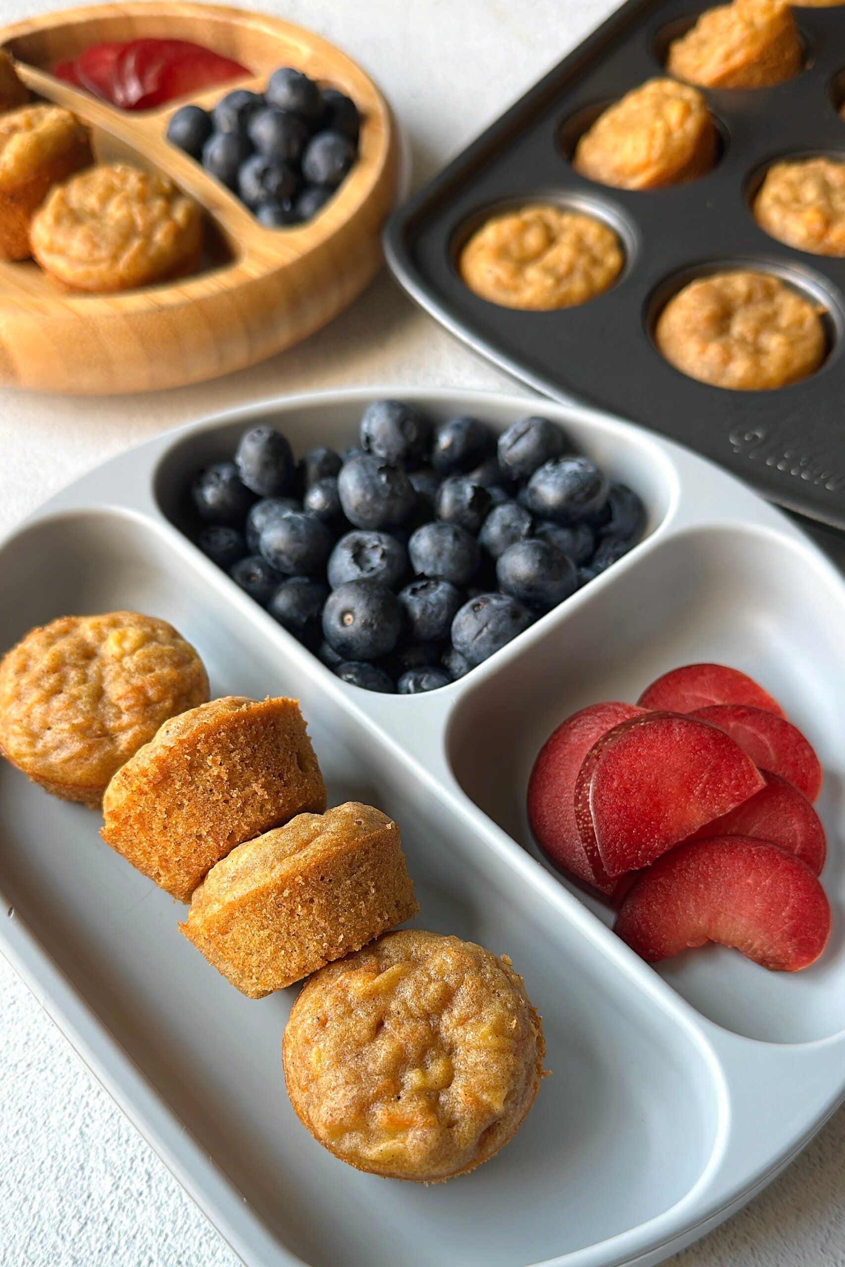Banana carrot muffins served with blueberries and plums.