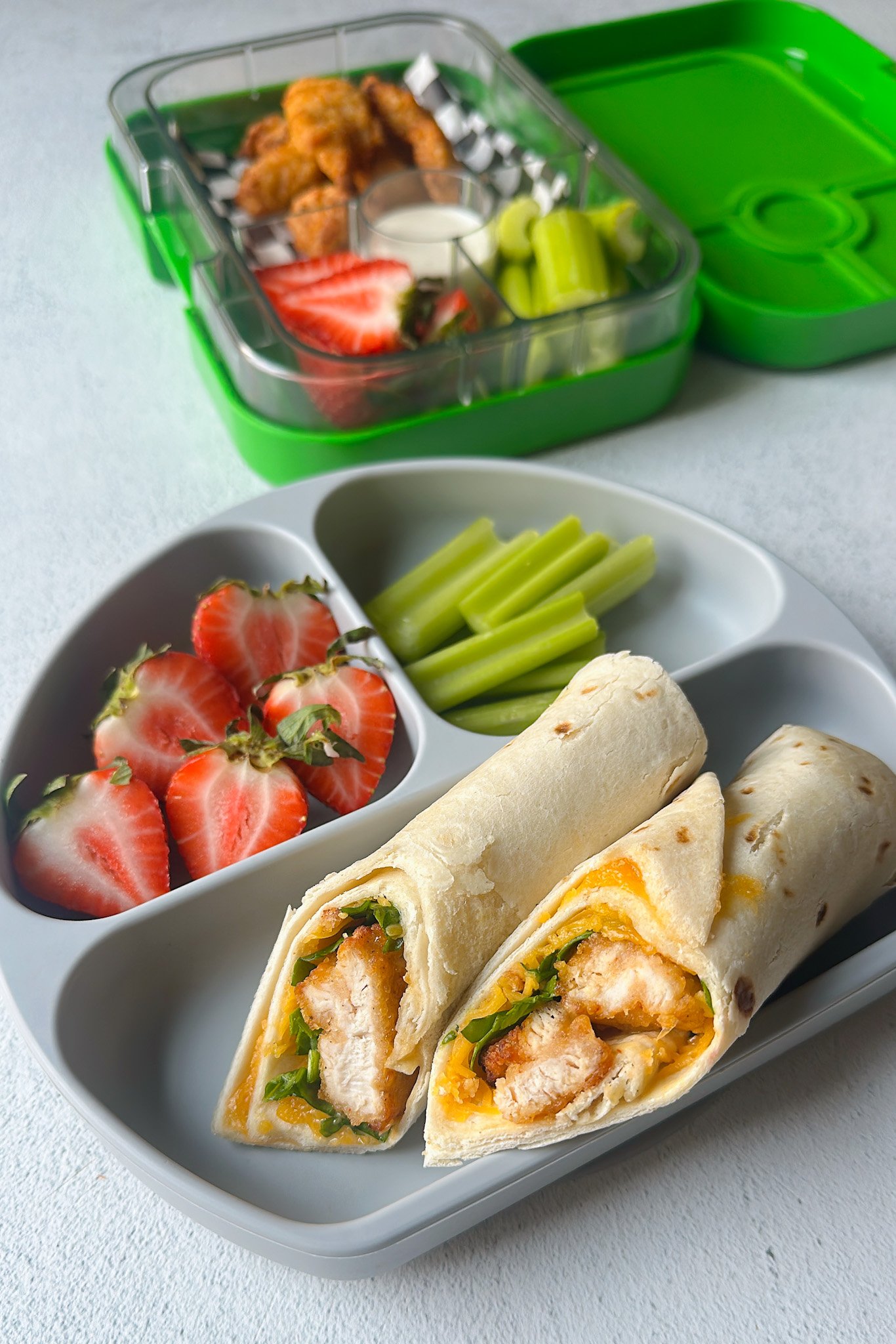 Chicken nuggets wrap served with strawberries and celery.