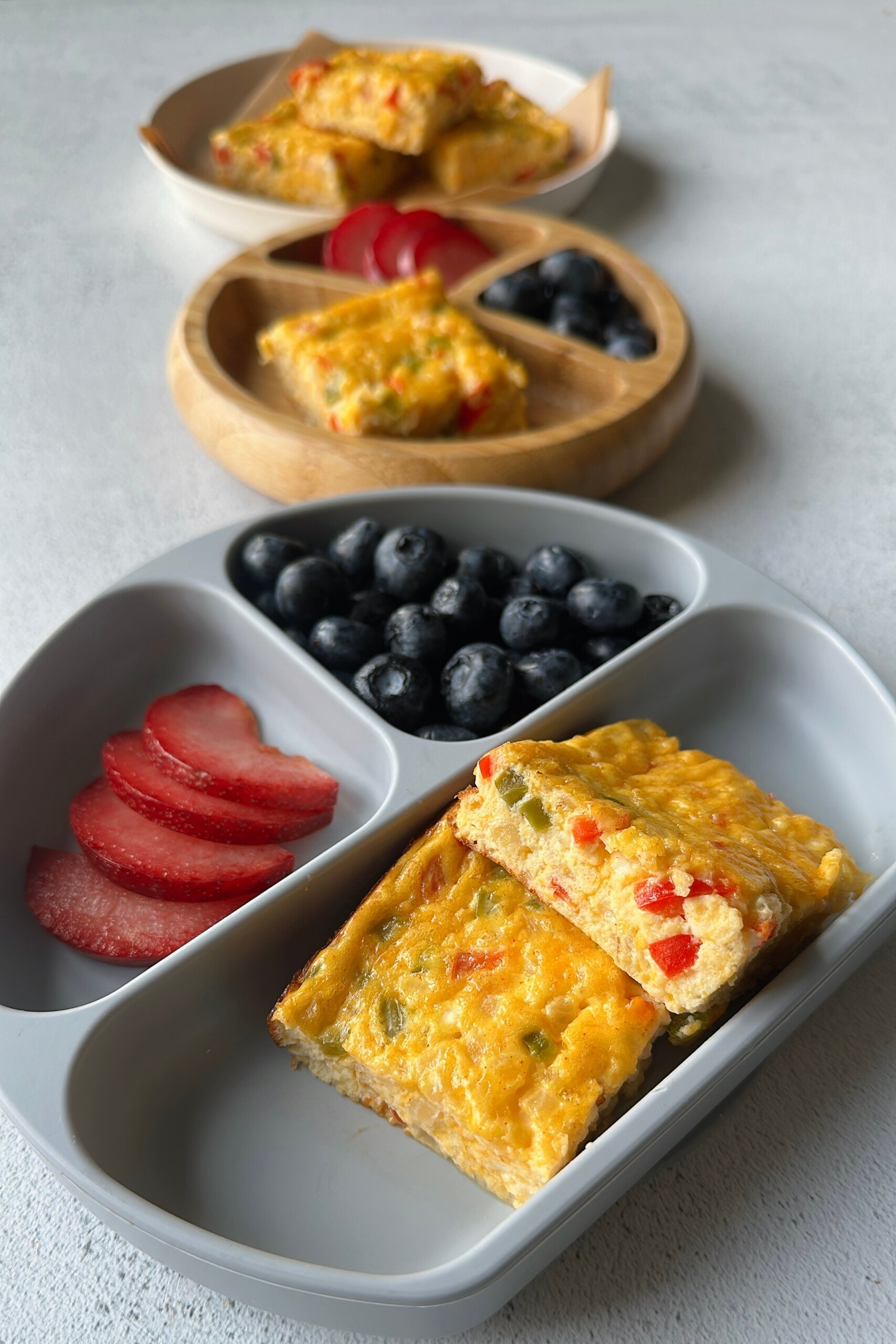 Cottage cheese egg casserole served with plum slices and blueberries.