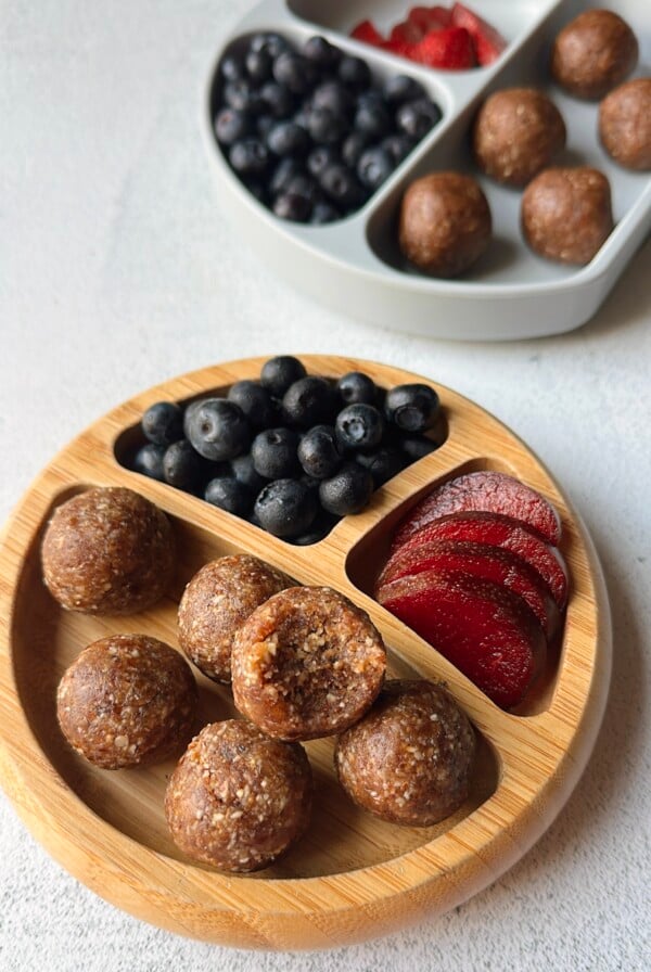 Date bites served with plums and blueberries.