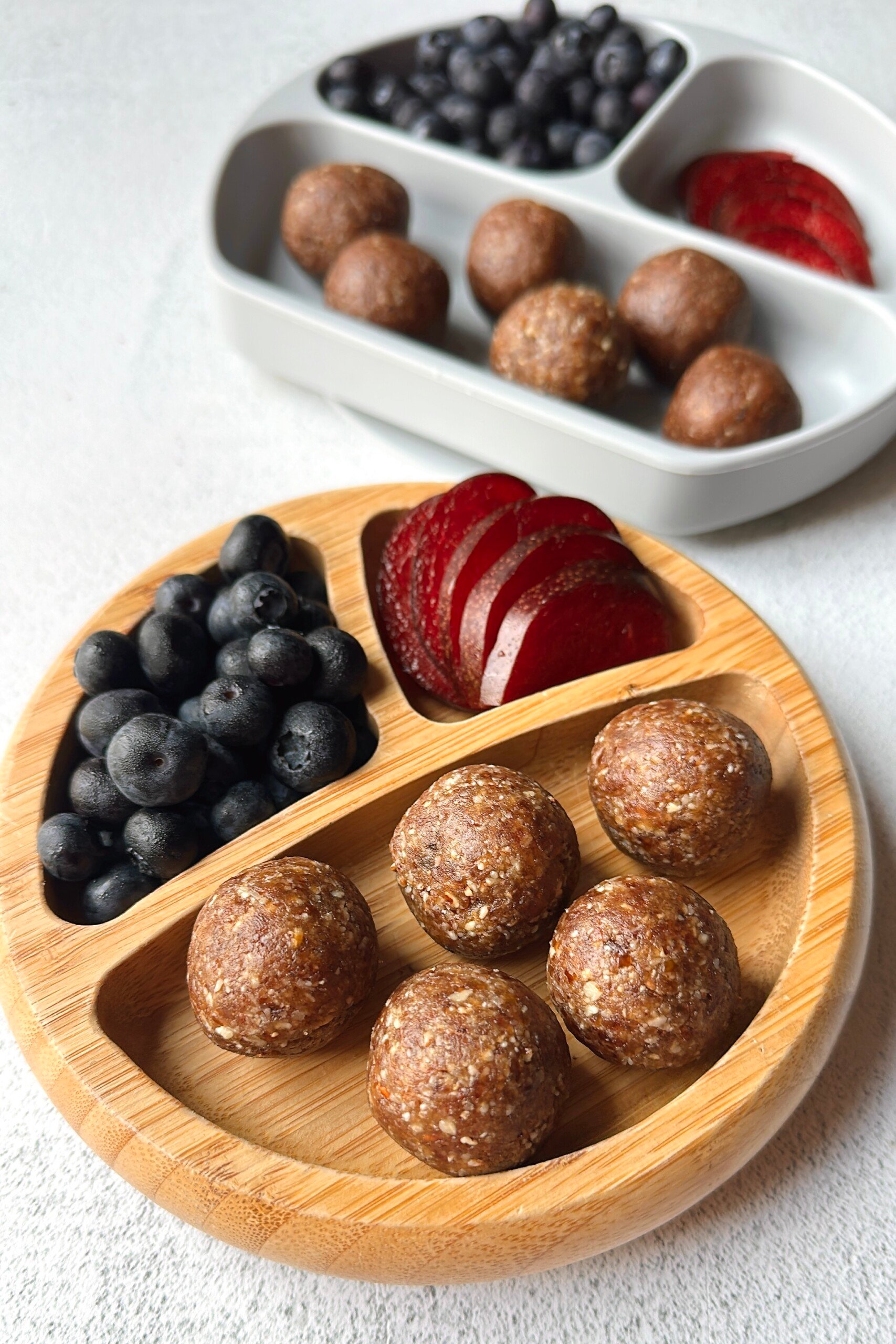Date bites served with plums and blueberries.