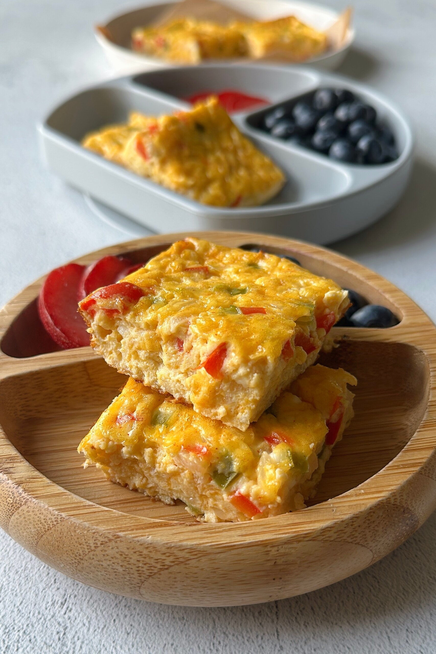 Cottage cheese egg casserole served with plum slices and blueberries.