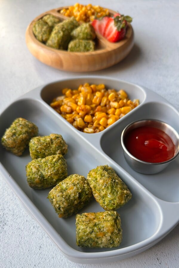 Broccoli tots served with ketchup, corn, and berries.