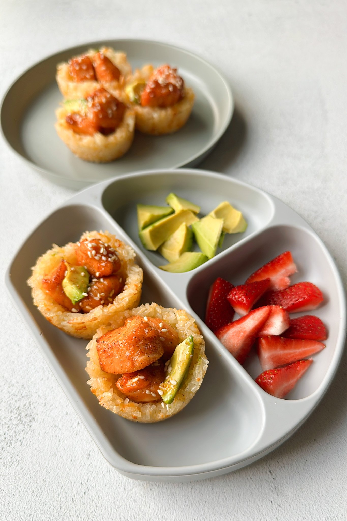 Cheesy salmon rice cups topped with honey salmon and served with avocado and strawberries.