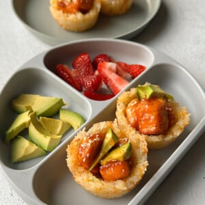 Cheesy salmon rice cups topped with honey salmon and served with avocado and strawberries.