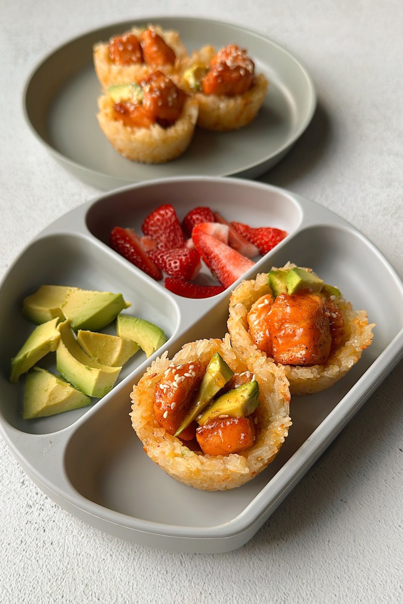 Cheesy salmon rice cups topped with honey salmon and served with avocado and strawberries.