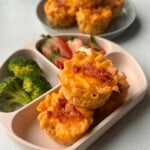 Mac and cheese muffins served with strawberries and broccoli.